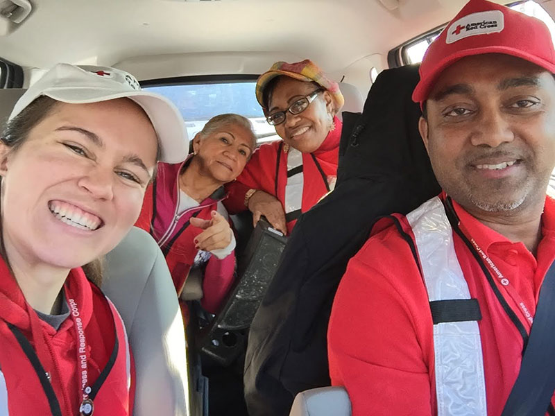 4 Red Cross volunteers in car smiling for the camera