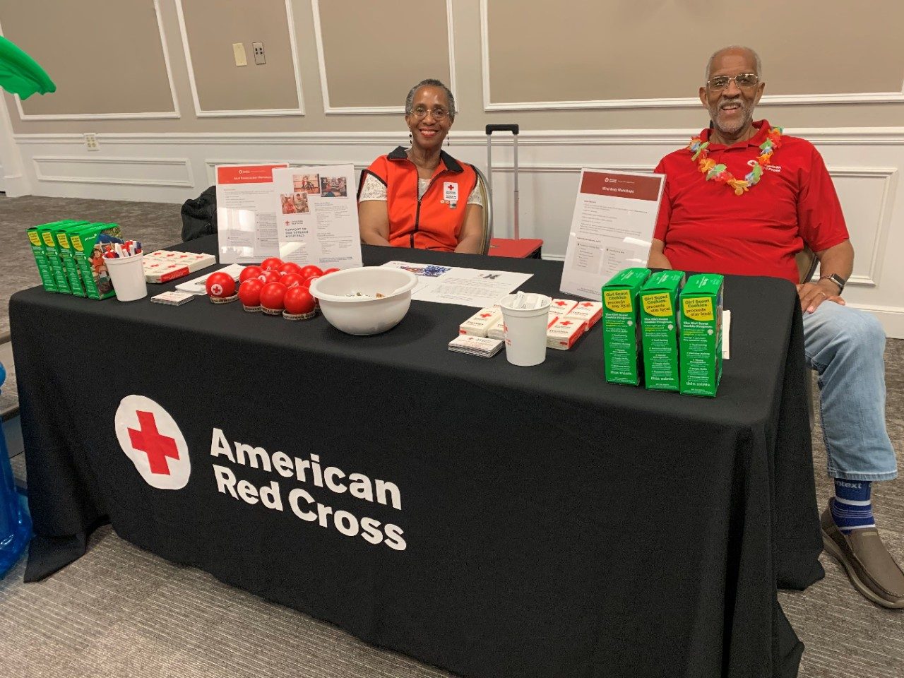 two red cross volunteers at a table with red cross supplies