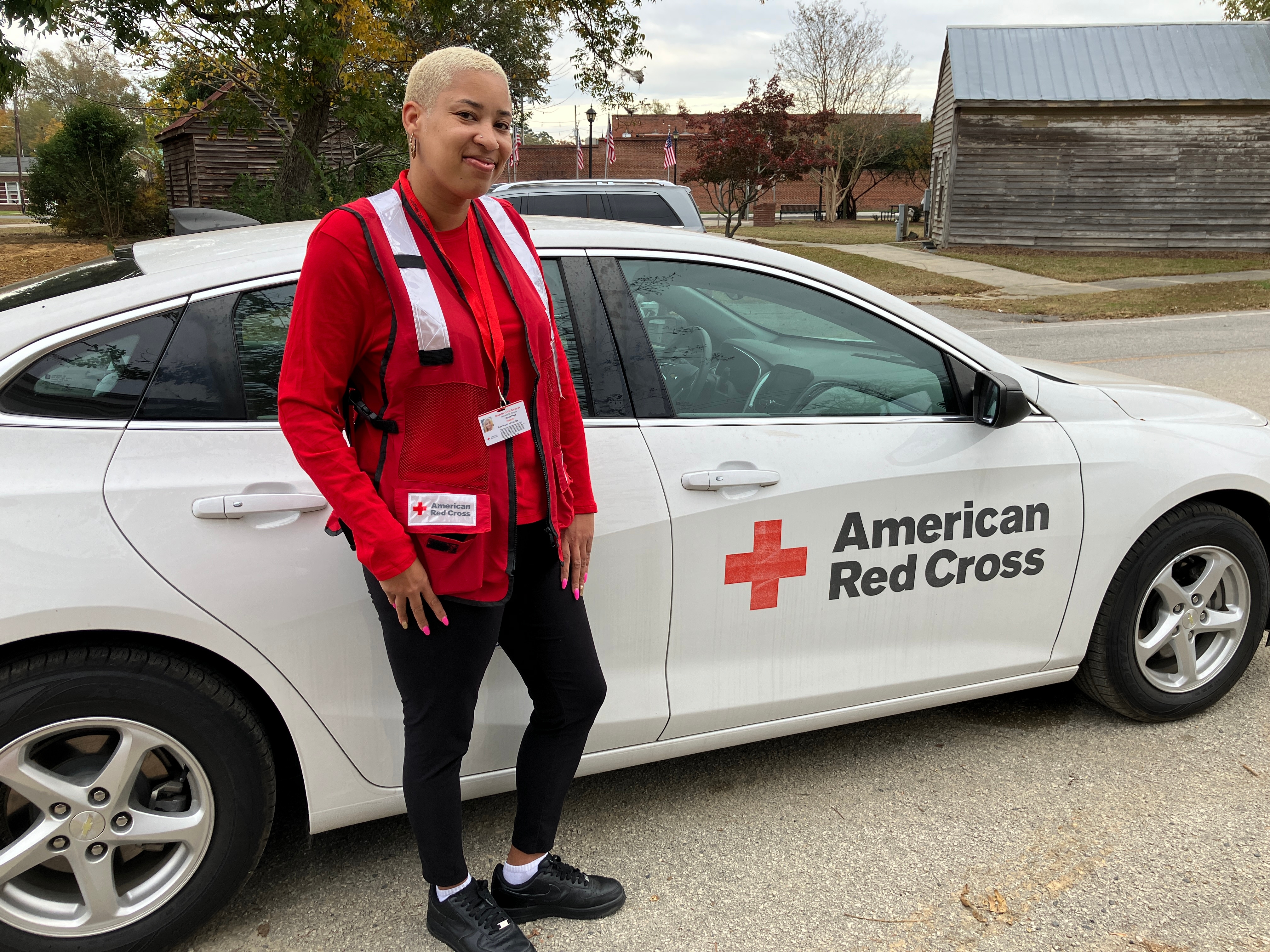 red cross volunteer next to red cross car