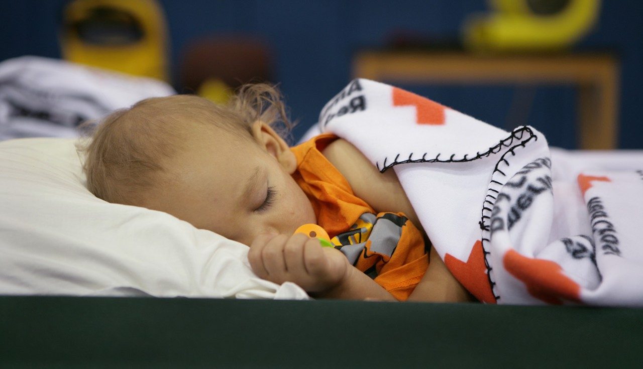 Child sleeps in a Red Cross shelter