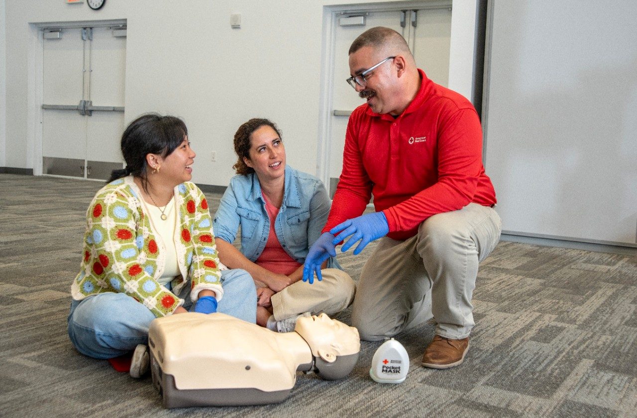 A Red Cross volunteer gets set up to demonstrate CPR on a test dummy.