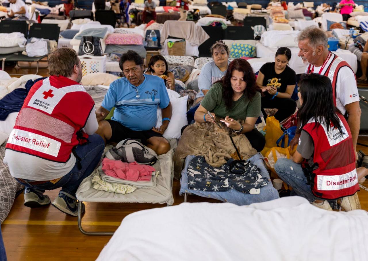 A family speaks with Red Cross staff members at an emergency shelter at the War Memorial Gymnasium in Wailuku on Maui