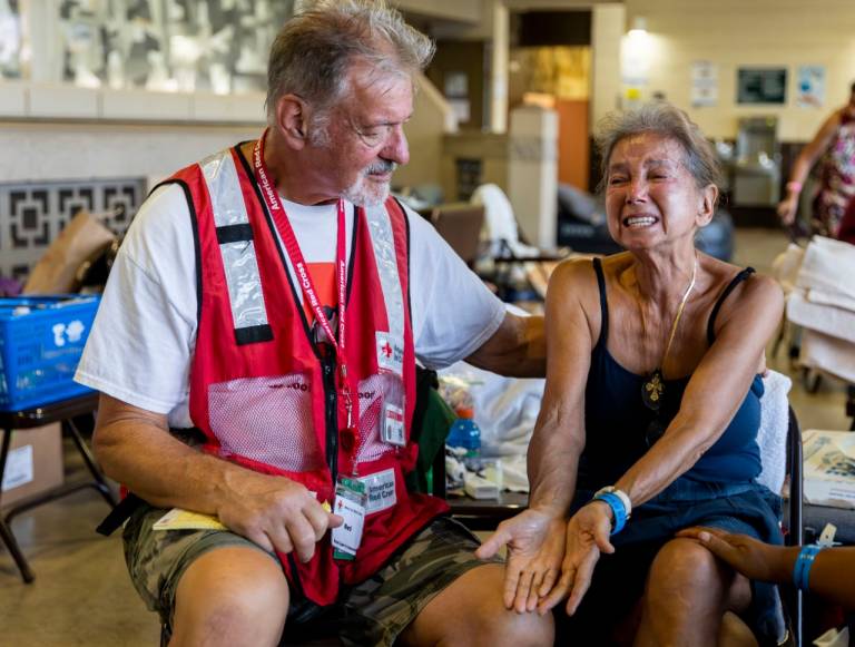 American Red Cross volunteer comforts Elaine Goode at the Red Cross shelter at the War Memorial Gymnasium in Wailuku on Maui
