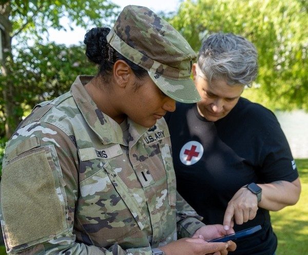Red Cross volunteer assists a uniformed servicemember