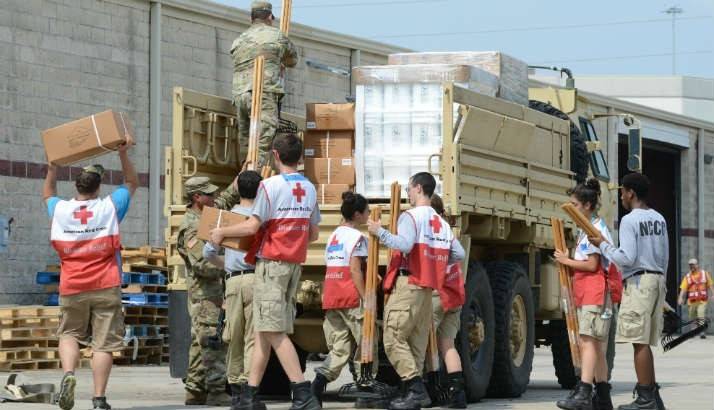 Volunteers and active-duty US Army service members work together to load three convoys of Army high-profile vehicles with supplies.