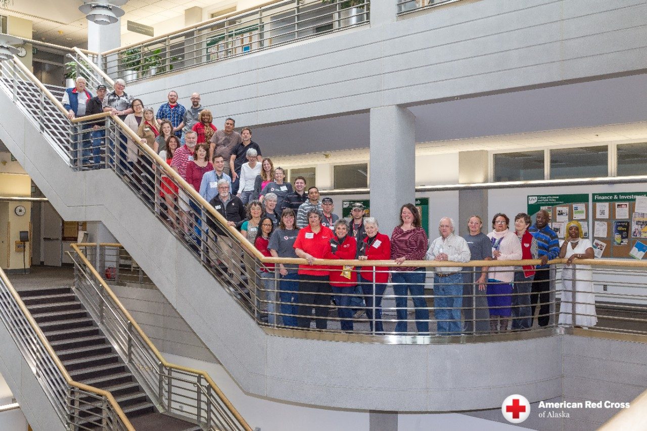 Large group of Red Cross volunteers posing on a staircase