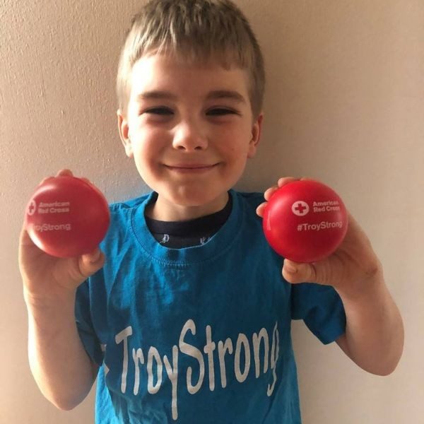 troy smiling holding two red cross balls