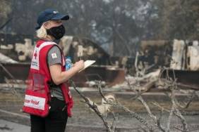 Red Cross volunteer with clipboard and pen looking at damage done by fire