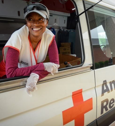 Smiling Red Cross volunteer leaning out the window of a Red Cross meals van