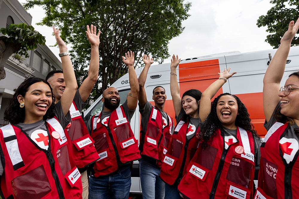 Group of Red Cross volunteers with their hands raised.