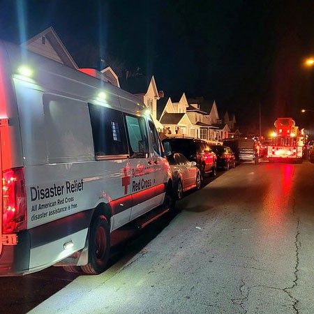 Red Cross Disaster Relief van and Fire truck on street at night.
