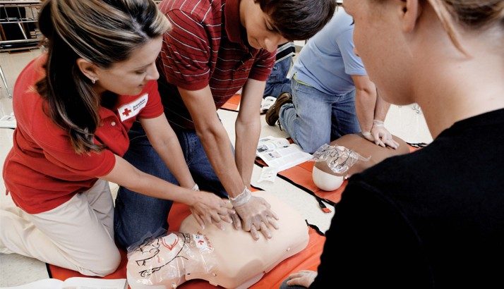 Students in a Red Cross CPR class practicing on a mannequin.