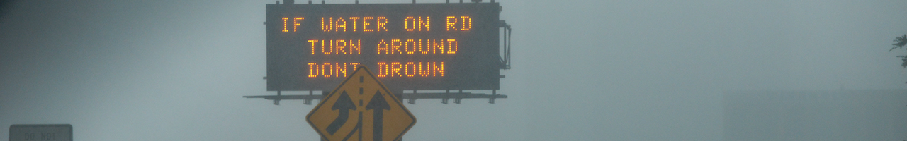 Warning sign on highway during rainstorm