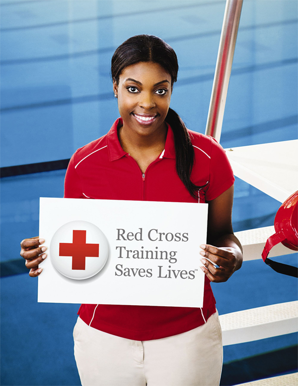 A Red Cross volunteer holding a sign that says Red Cross Training Saves Lives
