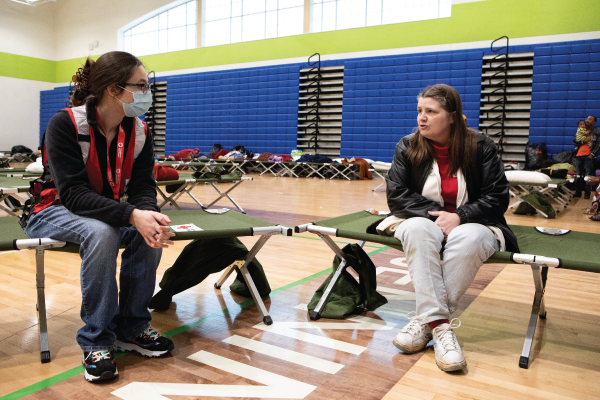 A Red Cross volunteer talking to a woman in a shelter.