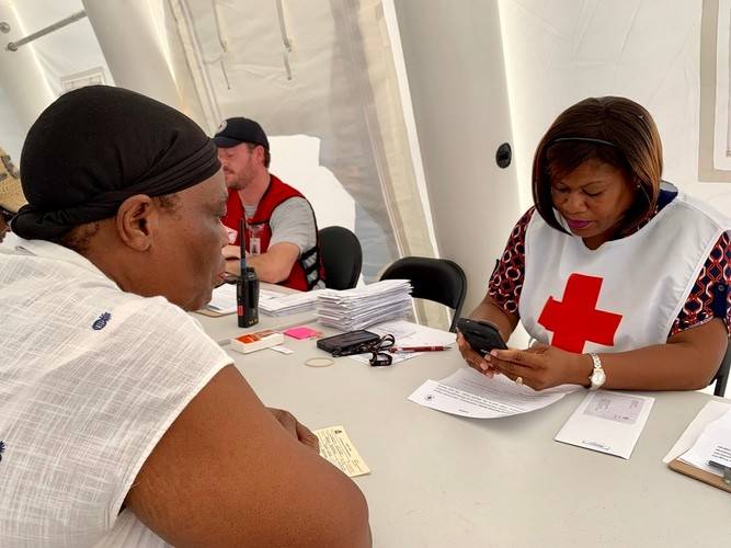 Bahamas Red Cross volunteer Pamela helps her neighbor to obtain aid