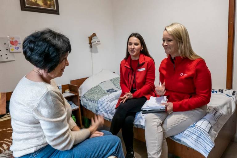 Red Cross volunteers speak with Liubov in shelter