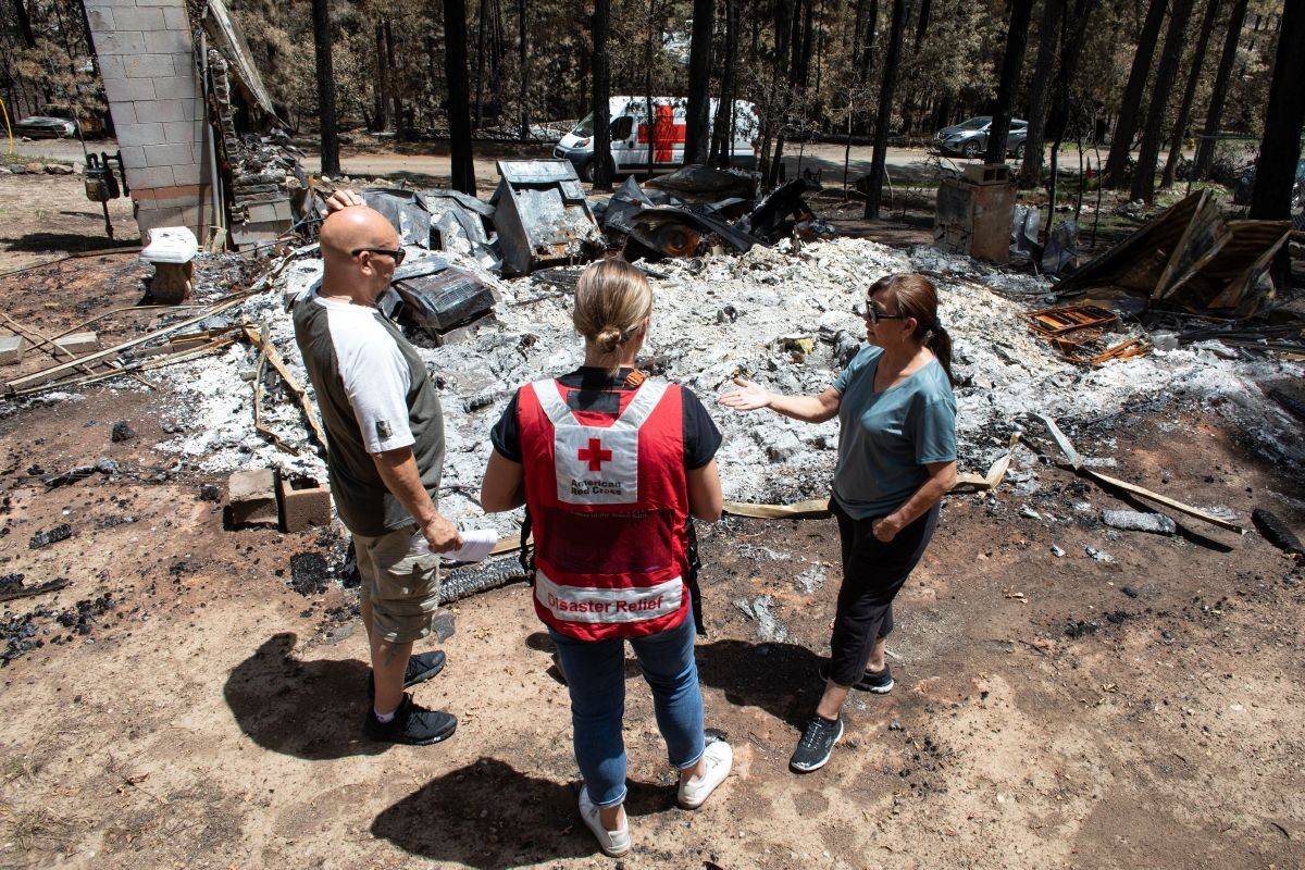 Part-time Ruidoso residents, Mike and Lucy Carzoli show Red Cross disaster worker what is left of their cabin.