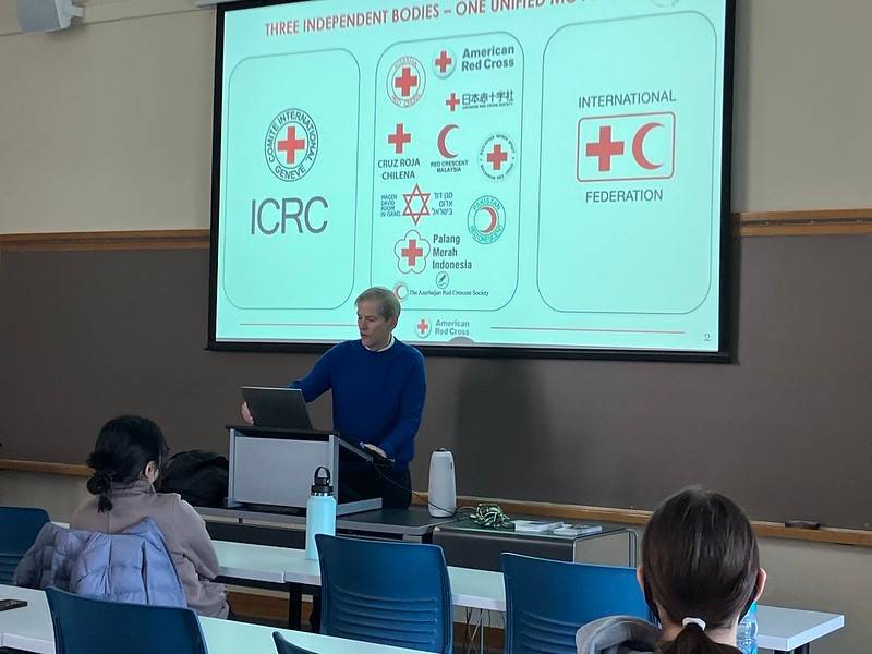 Craig Smith is standing in a conference room teaching a class on International Humanitarian Law