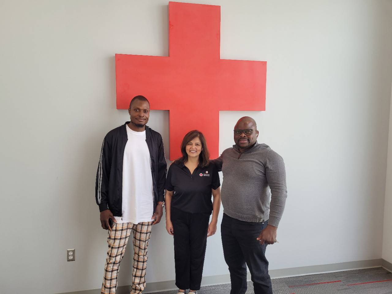 Franck and Ray smile with their Restoring Family Links caseworker Muneera. Muneera helped Franck reconnect with his sister after eight long years.