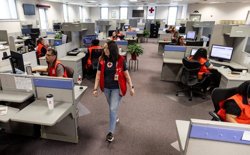 Muchos voluntarios de la Cruz Roja están trabajando frente a sus computadoras en un Hero Care Center.