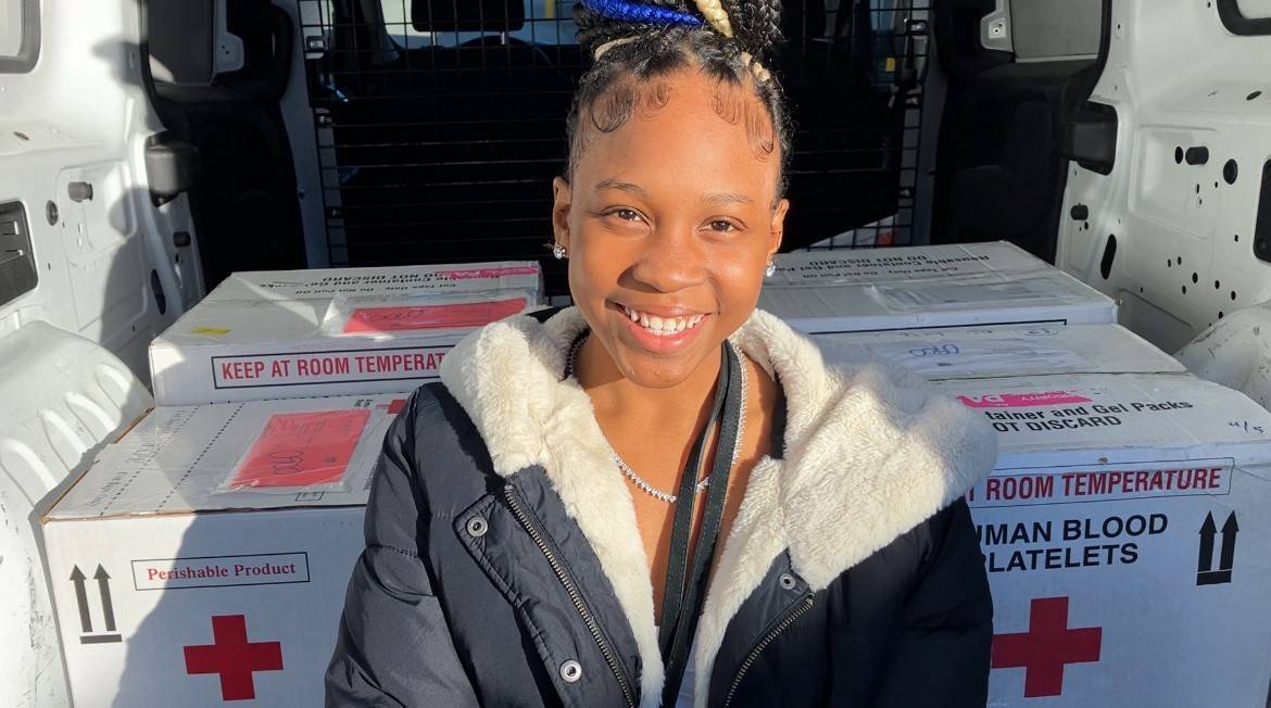 Tymia Green, who has sickle cell disease and has received 130 blood transfusions, participates in a ride along with an American Red Cross transportation specialist to deliver blood products for hospital patients