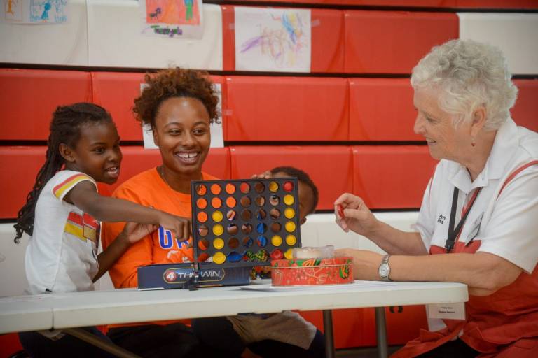 Red Cross volunteer, plays a game with 2-year-old Antoine and 7-year-old Tessiyah 
