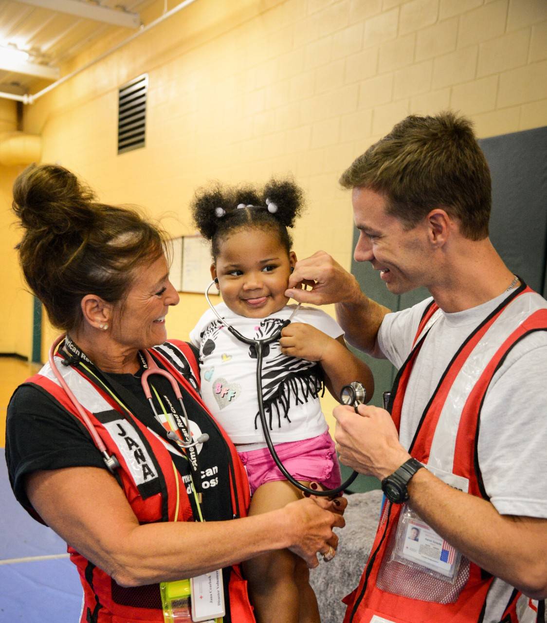 September 5, 2019. Jacksonville, Florida.
American Red Cross nurse Jana Cearlock and volunteer Aaron Arrants let 2-year-old Karmin Nelson listen through Nurse Jana’s stethoscope. Karmin and her great-grandmother, Minnie McDonald came to the evacuation shelter at the Legends Center to find a safe haven as Hurricane Dorian passed near the Jacksonville area.
Photo by Daniel Cima/American Red Cross