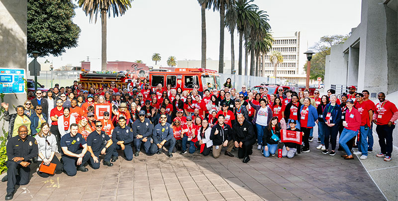 Large group photo of Red Cross volunteers and firefighters in front of fire engine