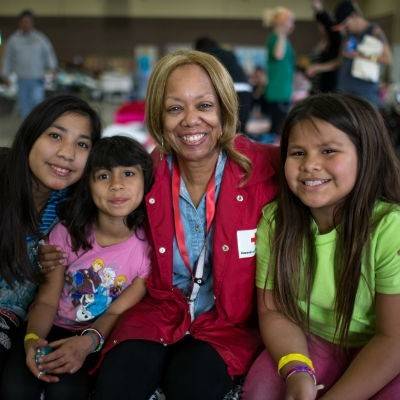 Red Cross volunteer sitting and smiling with family in shelter