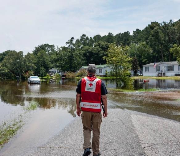 A Red Cross volunteer stands overlooking a flooded neighborhood. 