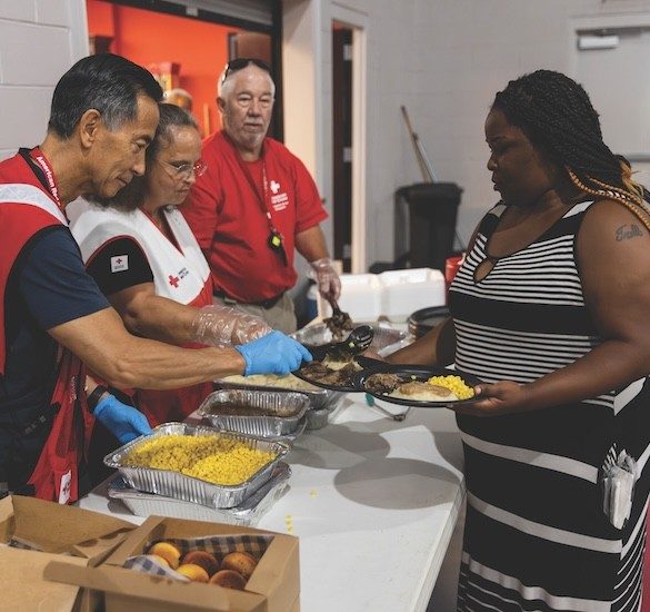 Volunteers in a shelter hand out meals to shelter residents