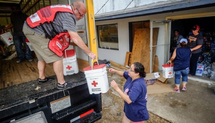 Voluntario de la Cruz Roja y colaboradores entregan kit de limpieza en una comunidad.