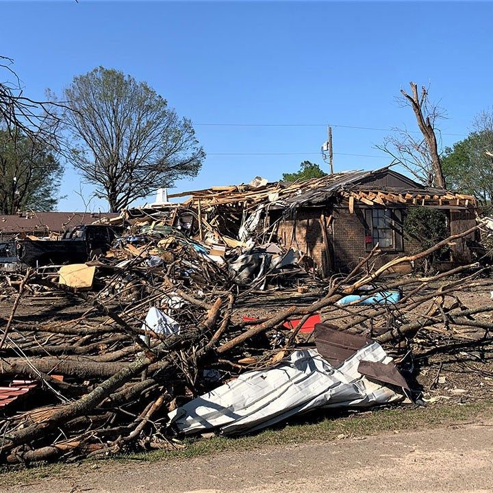 Damaged house, fallen trees and debris caused by a tornado.