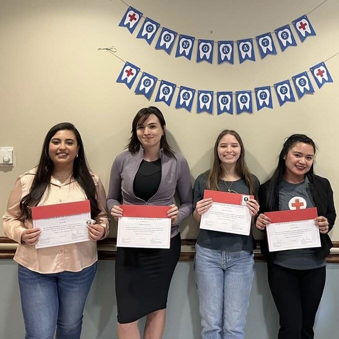 Four dental assistant training program graduates holding their certificates of completion.