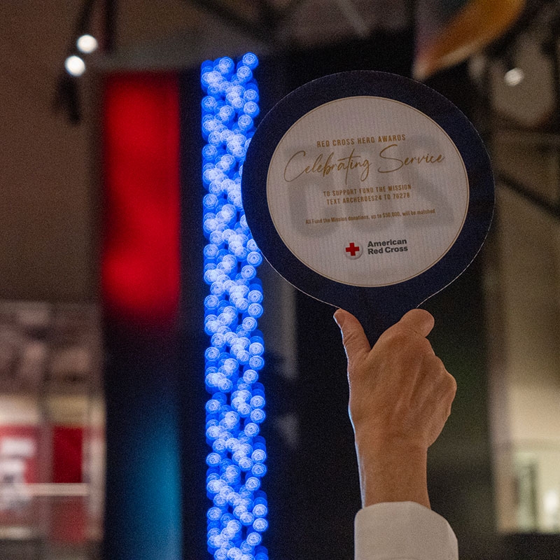 Hand holding up an American Red Cross auction paddle.