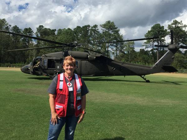 Red Cross volunteer Shellie Creveling stands in front of a National Guard helicopter