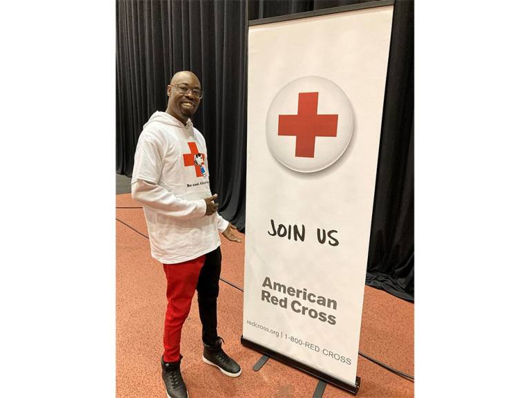 Thomas Carter standing next to Red Cross banner