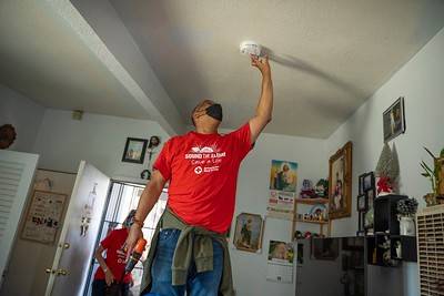 Red Cross volunteer installing smoke alarm on a ceiling