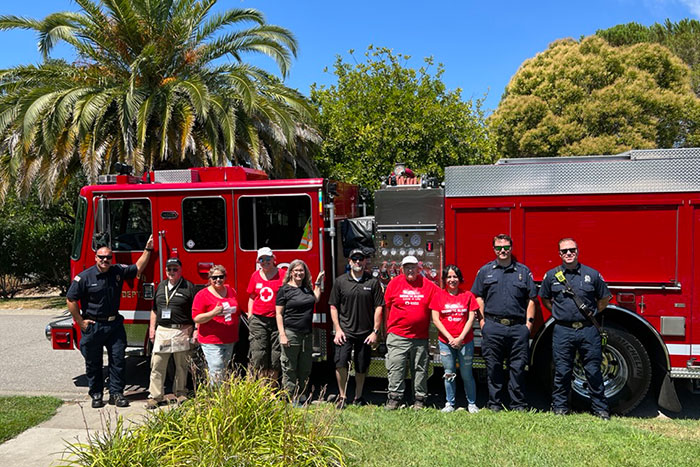 Red Cross volunteers and Firefighters standing in front of fire truck