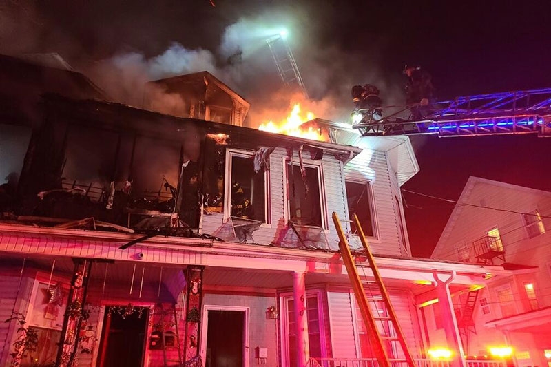 firefighters on ladder putting out house fire.