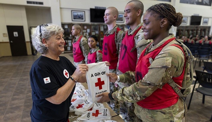 military members in camo clothing receiving Red Cross gift bags.