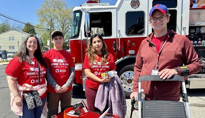 group of red cross volunteers wearing Sound the Alarm shirts and standing in front of a fire engone.