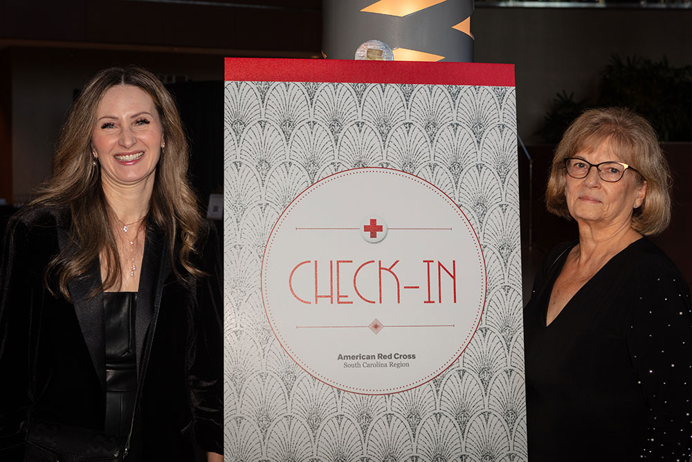 Two Red Cross Gala guests standing next to check-in sign.