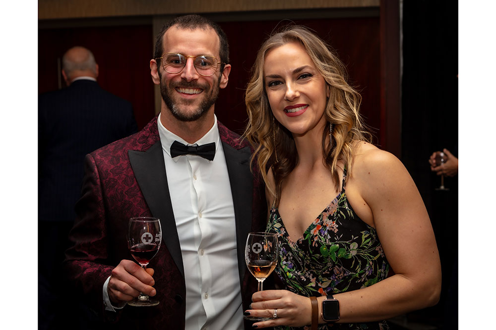 Couple holding wine glasses pose for a picture at the Red Cross Gala.