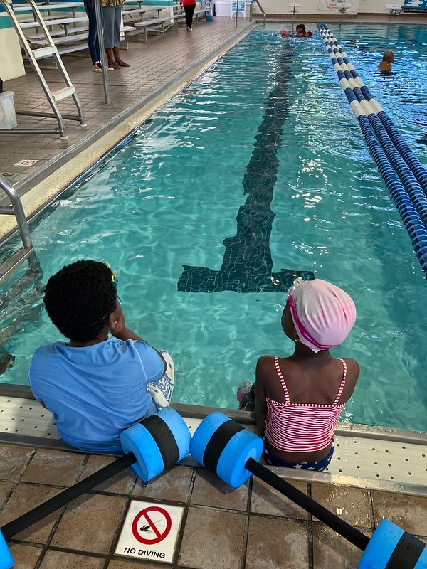 two children sitting at end of pool