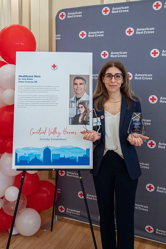 eliana troncale, rn next to poster with photo of dr. john bilello