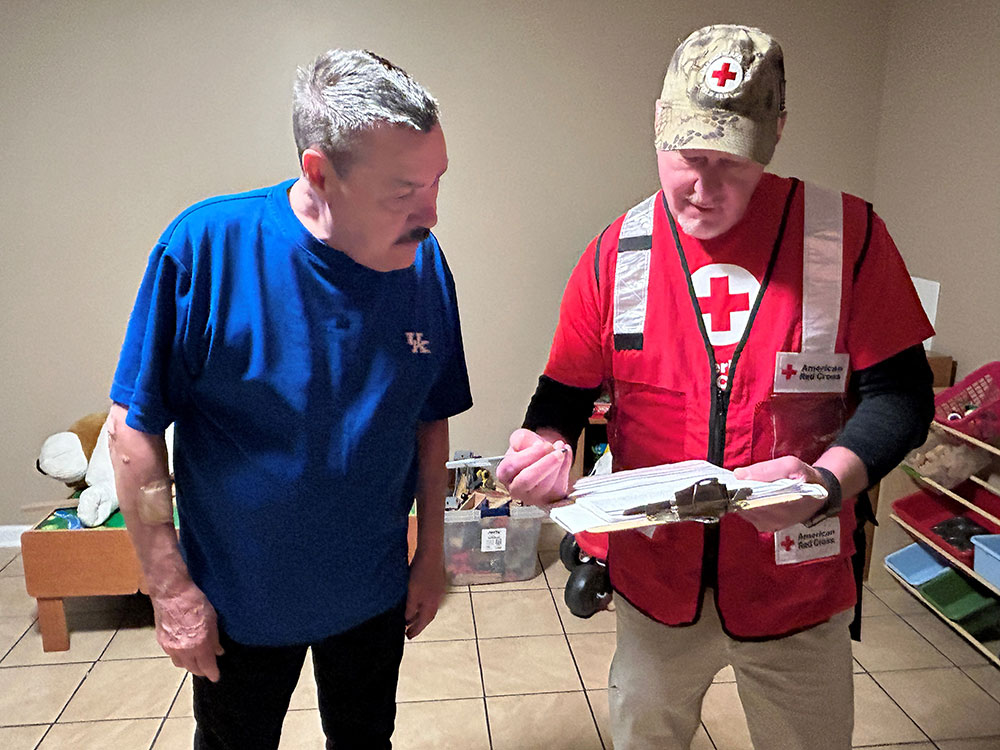 Red Cross volunteer showing man escape plans