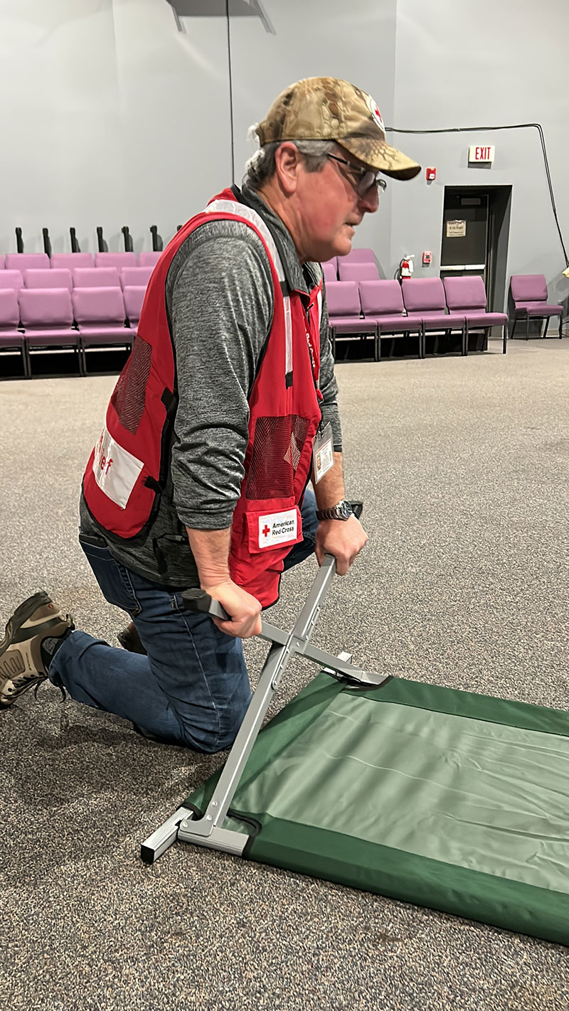 Red Cross volunteer setting up a cot.