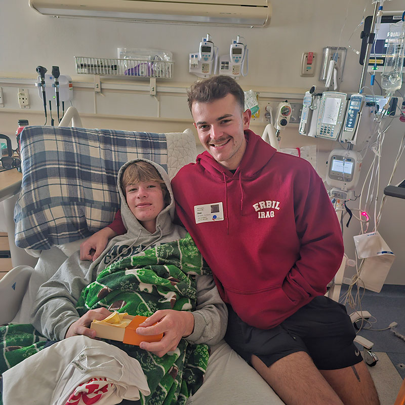 Boy in hospital bed with his brother sitting beside him